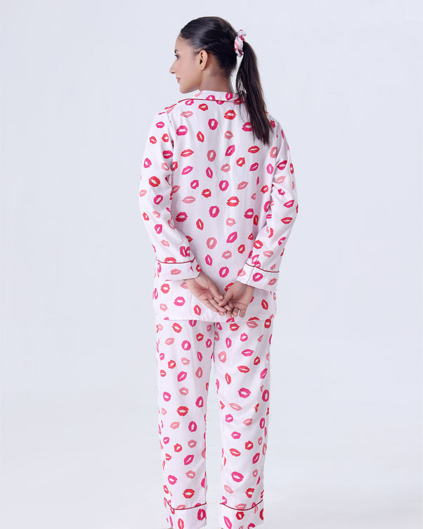 Person wearing a white pajama set with pink lip prints on a white background