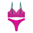 Pink lace lingerie set with green straps on a white background