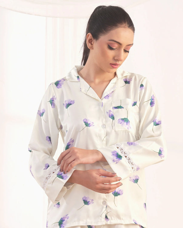 Woman wearing a white floral pajama set against a plain background