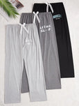 Two pairs of pajama pants, one gray and one black with text, on a white background.