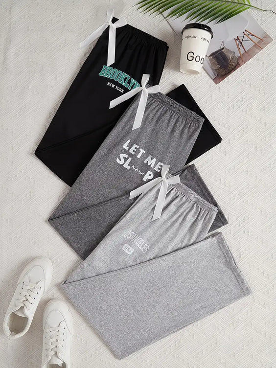 Gray and black pajama sets with text on a light gray surface, accompanied by white sneakers and a coffee cup.